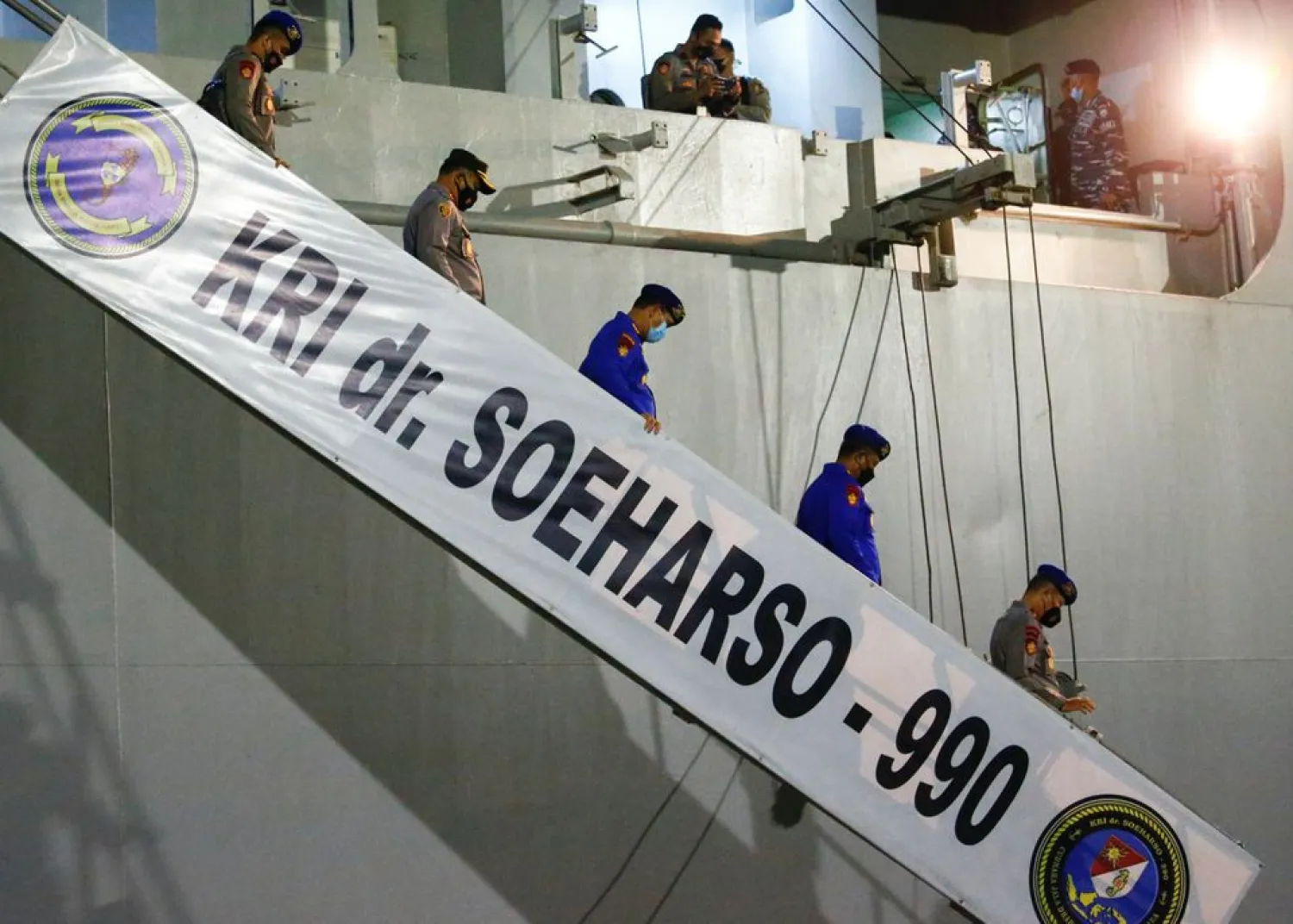 Indonesian police officers walk down the stairs of the ship KRI dr. Soeharso-990 at Tanjung Wangi port, as the search continues for the missing KRI Nanggala-402 submarine in Banyuwangi, East Java Province Indonesia, April 23, 2021. REUTERS/Ajeng Dinar Ulfiana