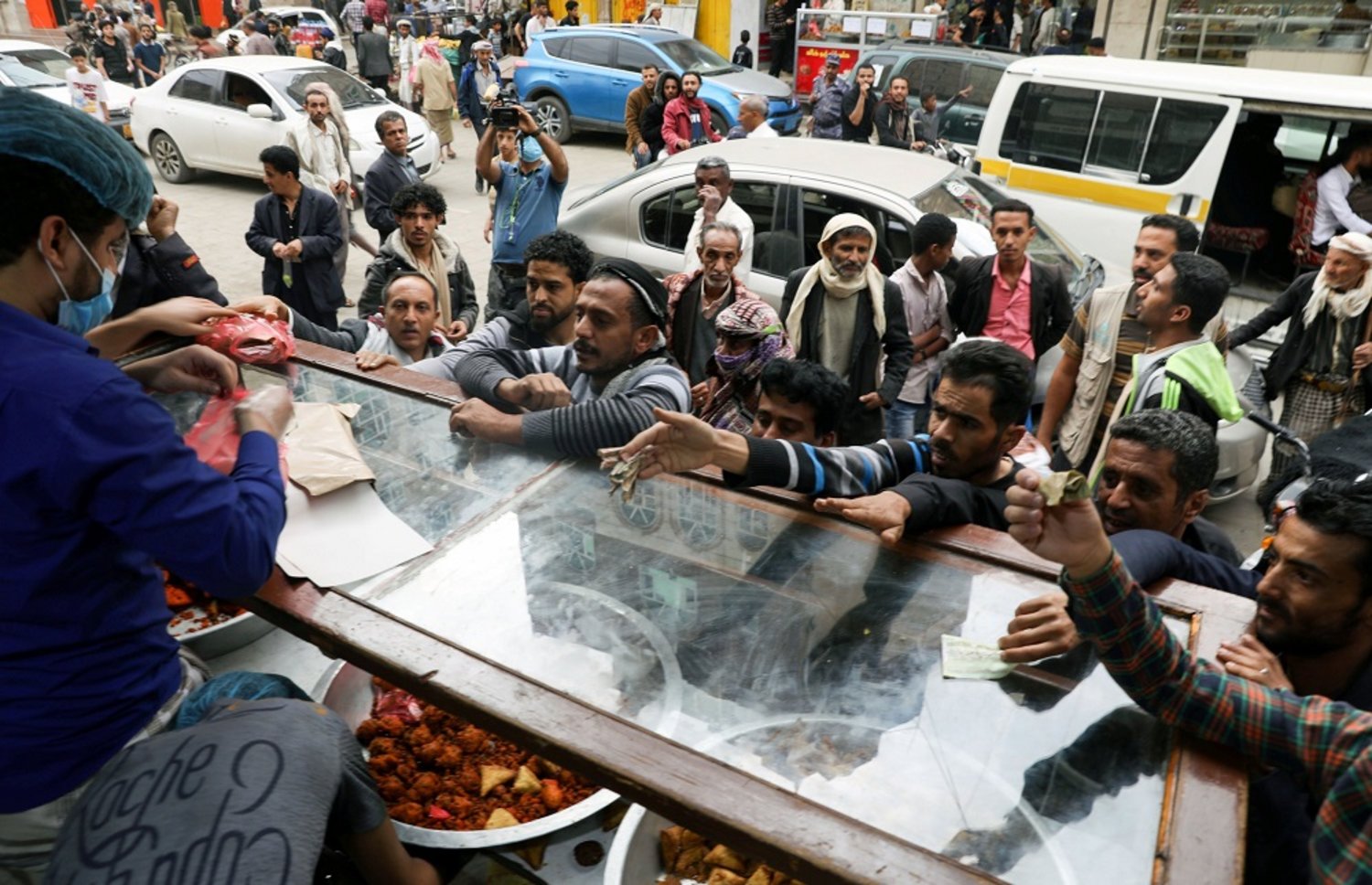 People gather outside a pastry shop to buy sambusa during the holy month of Ramadan in Sanaa, Yemen, April 15, 2021. (Reuters)