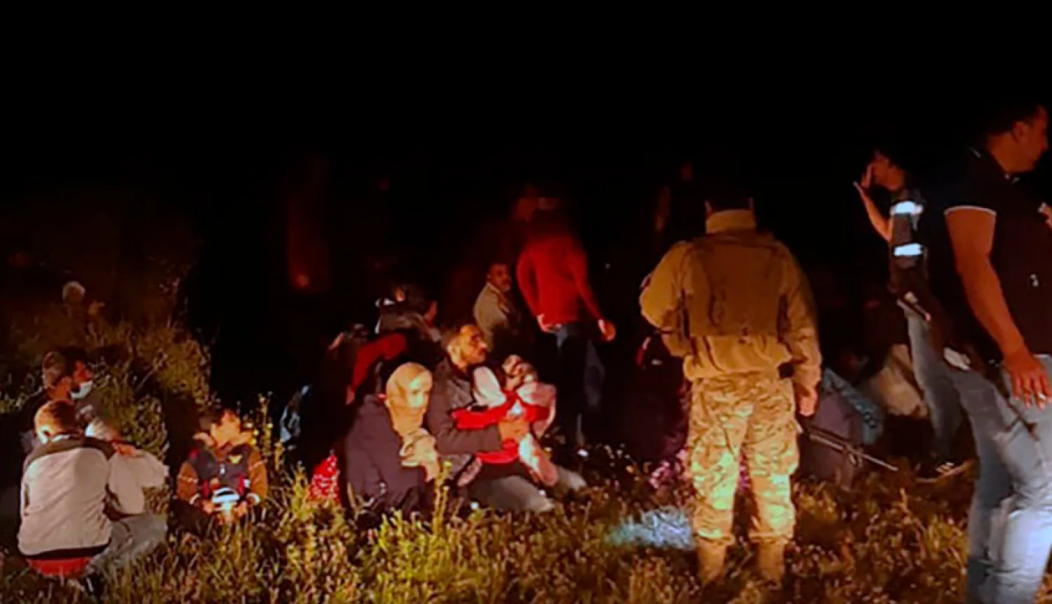 In this photo released by the Lebanese Army official website, Lebanese troops stand next to Syrian migrants who tried to go by boat to the Mediterranean island of Cyprus, in the northern region of Akkar near the border with Syria, Lebanon, early Sunday, April. 25, 2021. (Lebanese Army Website via AP)