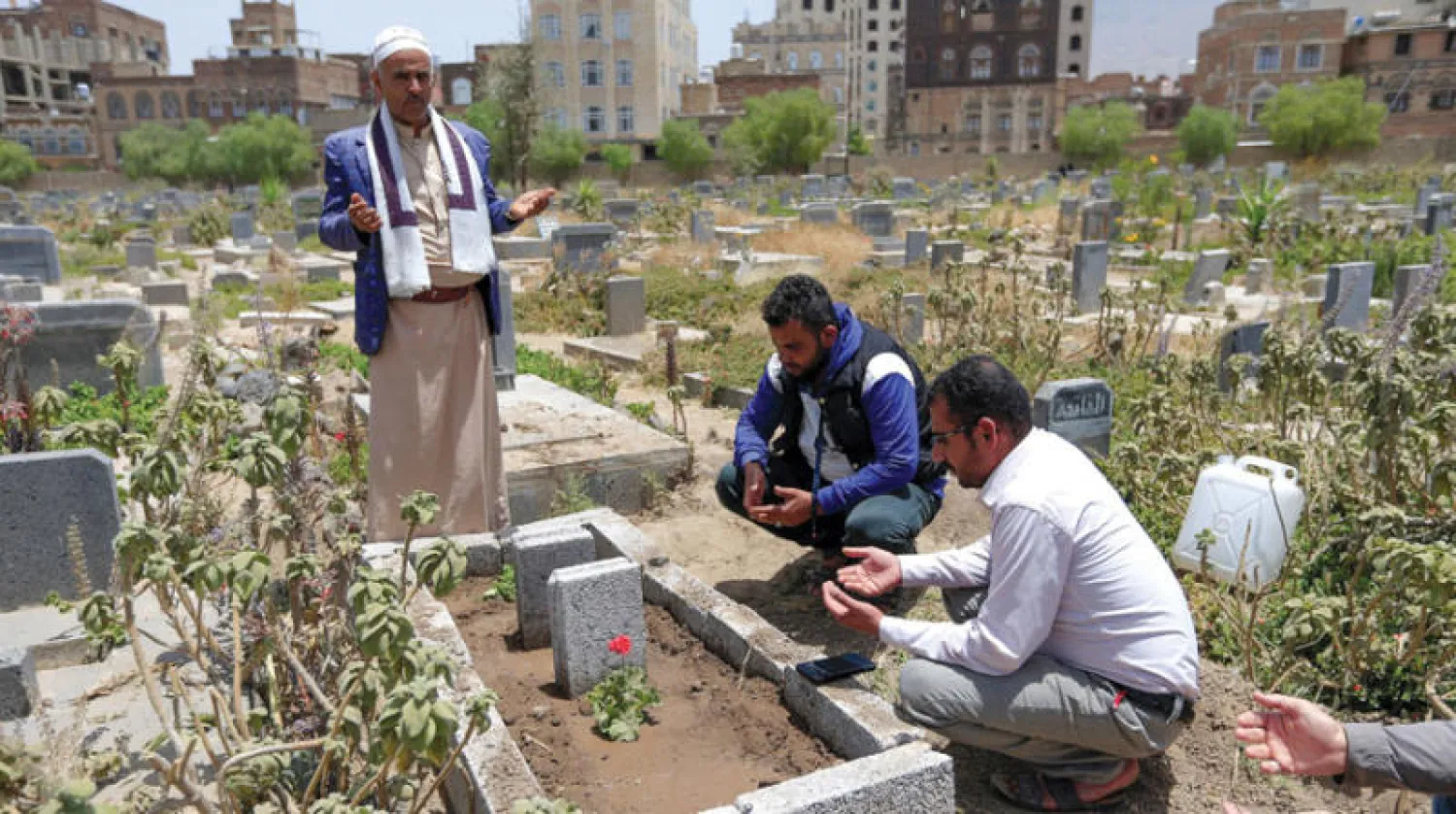 يمني عند قبر زوجته الحامل بعد رفض المستشفيات استقبالها خوفاً من «كورونا» (أ.ف.ب)