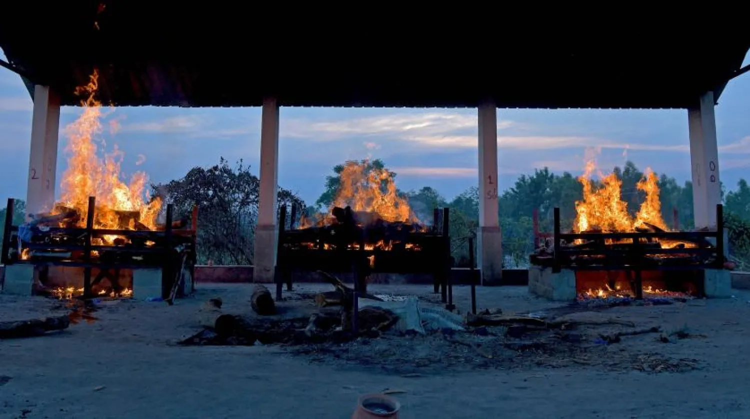 Koronavirüs nedeniyle hayatını kaybeden 3 insanın cesetleri yakılıyor (AFP)