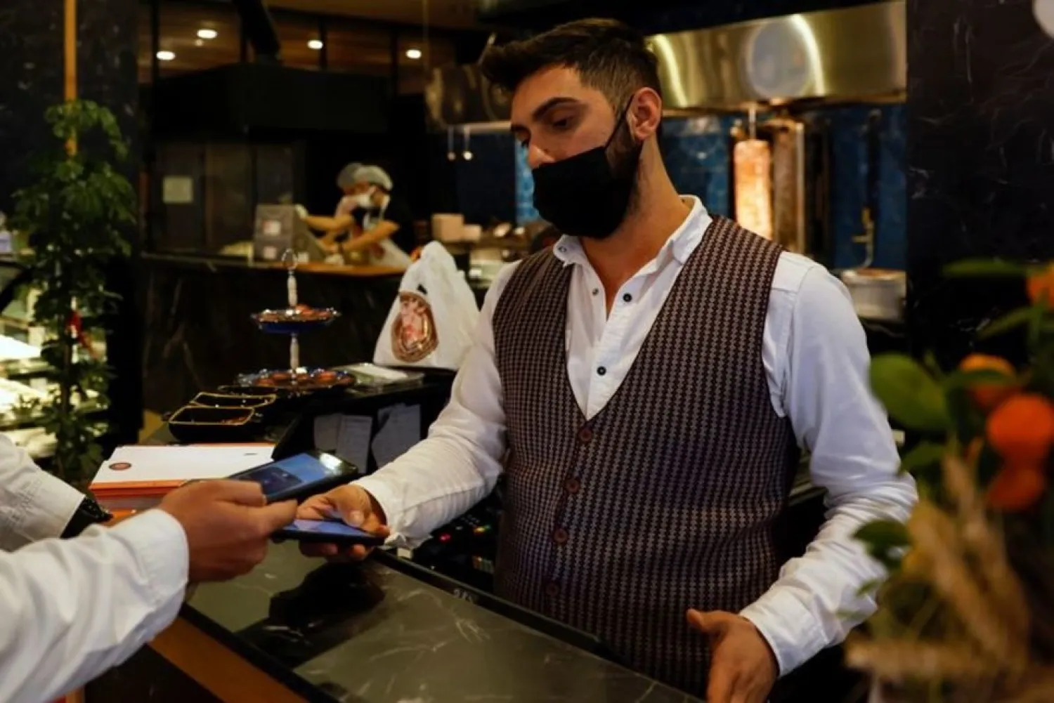 A cashier receives a payment via a cryptocurrency app at a kebab restaurant that accepts Bitcoin and Dexchain in Istanbul, Turkey, April 27, 2021. (Reuters)
