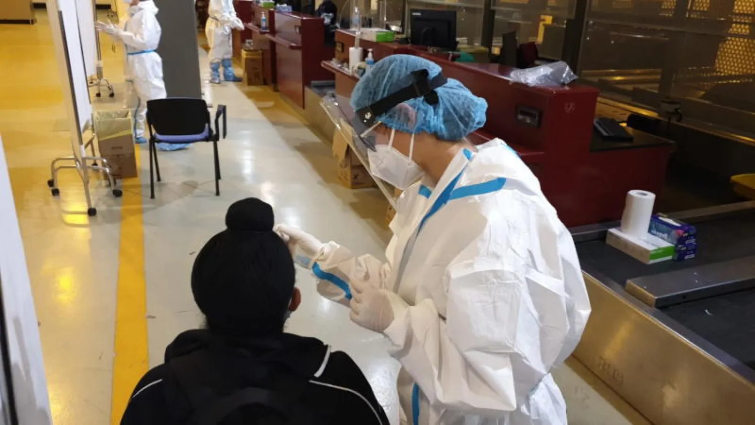 أفراد الأمن يفحصون درجة حرارة المسافرين الذين يصلون من الهند في مطار «روما ليوناردو دا فينشي الدولي» في فيوميتشينو بإيطاليا (إ.ب.أ)