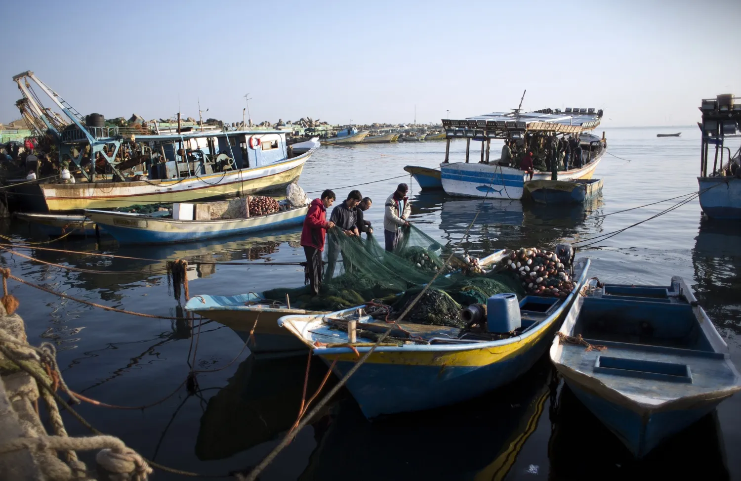Palestinian fishermen clean a net after a night fishing trip, in the Gaza Seaport on April 3, 2019. (AP Photo/Khalil Hamra)