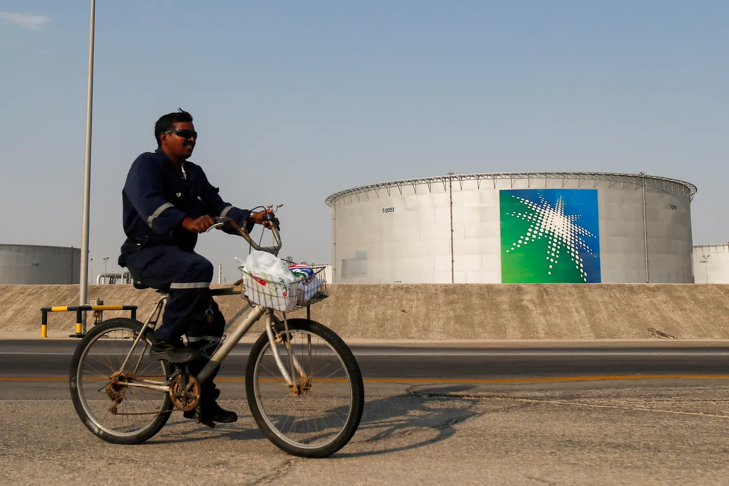 FILE PHOTO: An employee rides a bicycle next to oil tanks at Saudi Aramco oil facility in Abqaiq, Saudi Arabia October 12, 2019. REUTERS/Maxim Shemetov
