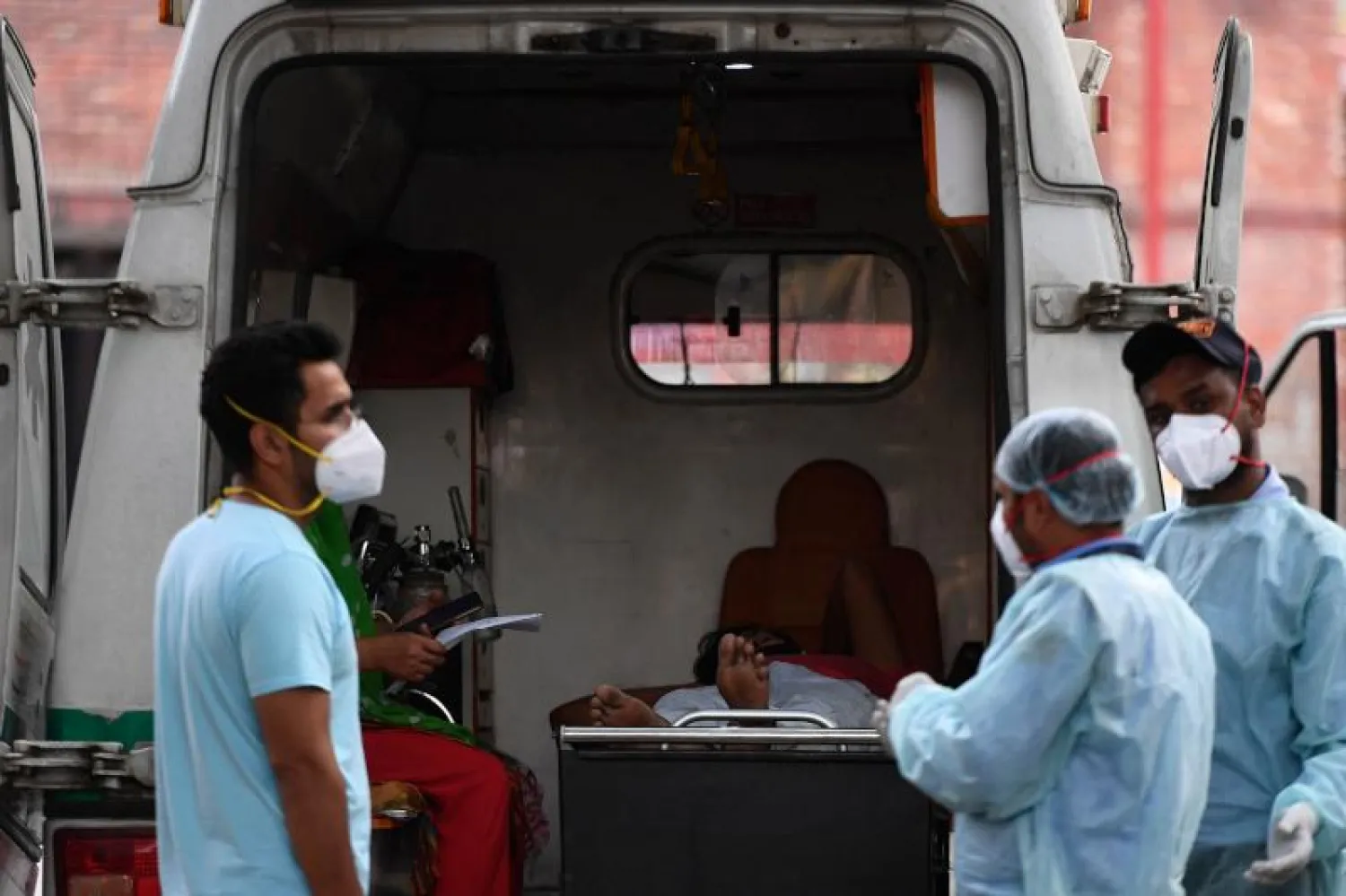 مريض مصاب بفيروس كورونا يستلقي في سيارة إسعاف أثناء انتظار دخوله إلى مستشفى في نيودلهي (أ.ف.ب)