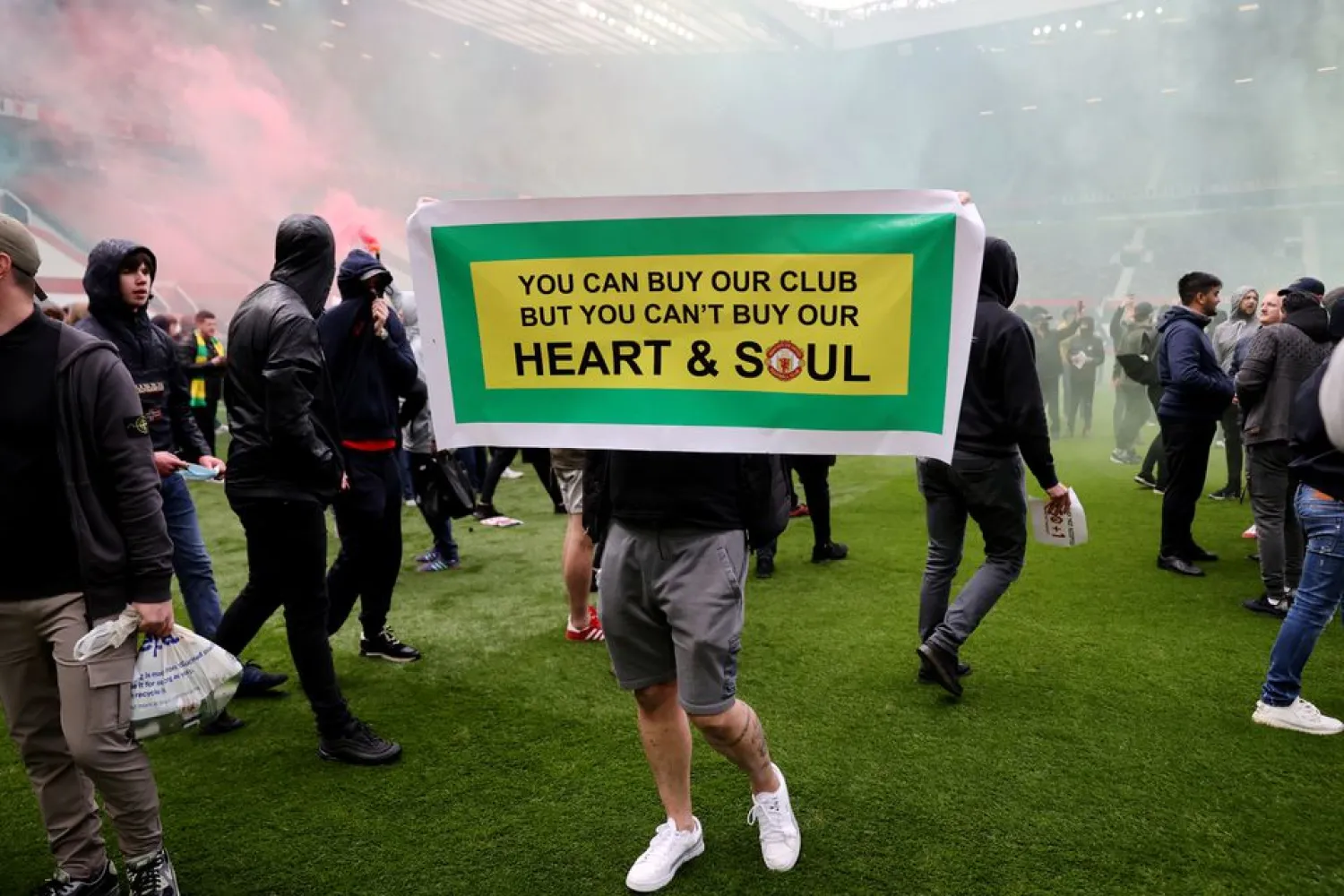 A Manchester United fan holding a banner on the pitch in protest against their owners before the match. (Reuters)
