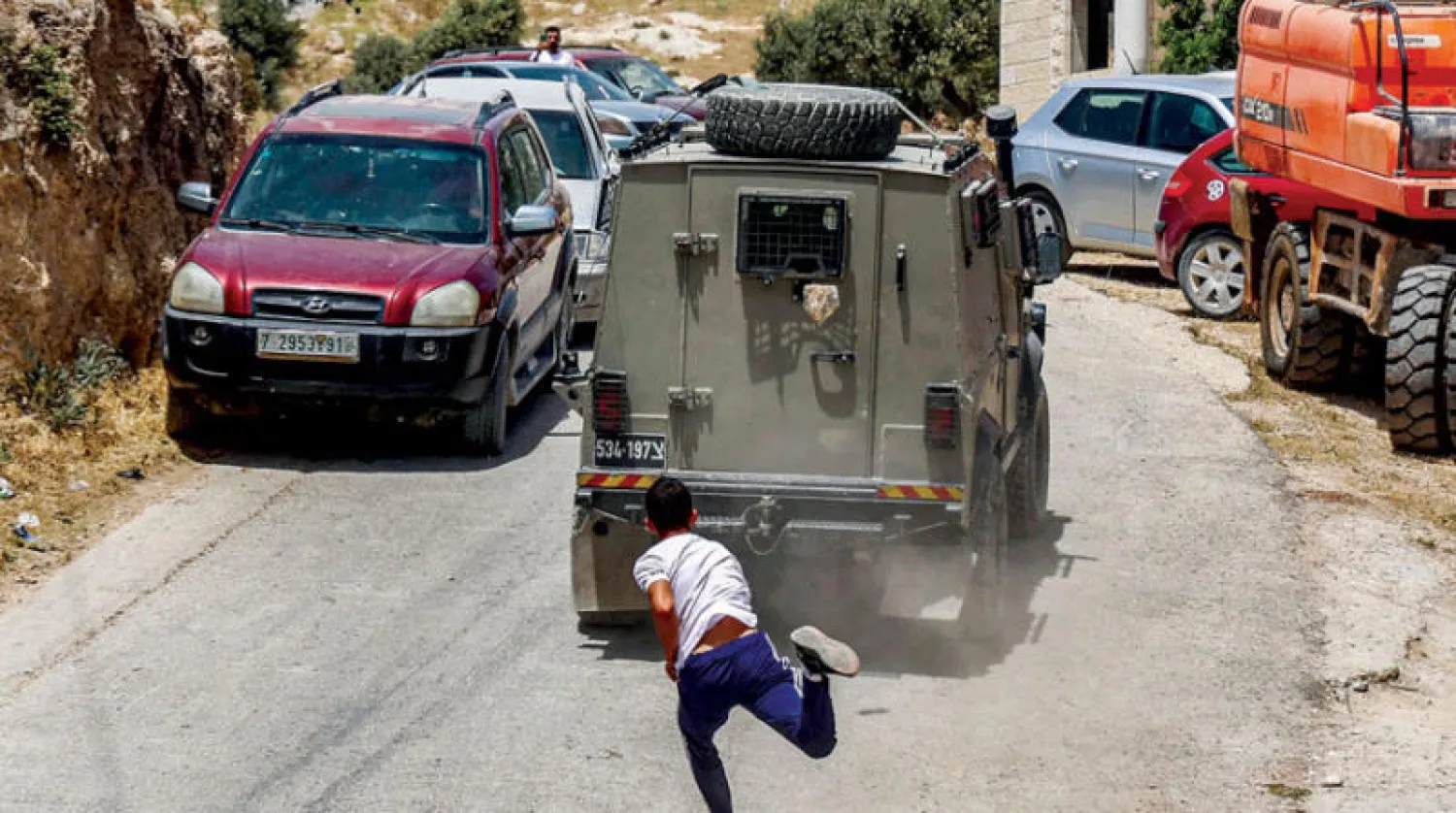 طفل فلسطيني يرمي عربة عسكرية إسرائيلية بحجر في بلدة عقربا (أ.ف.ب)