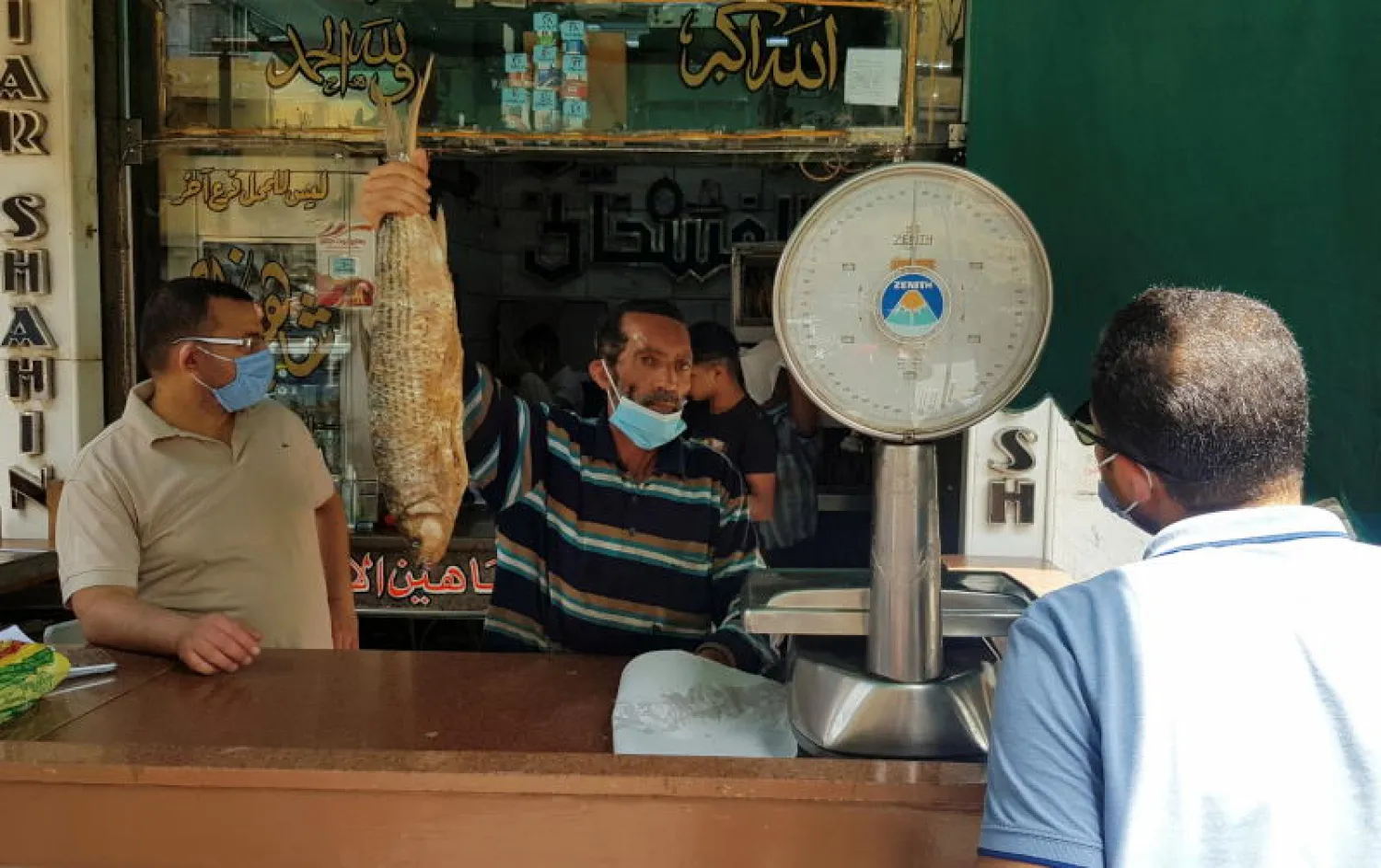 أشخاص يضعون الكمامات في إحدى الأسواق بالقاهرة (رويترز)