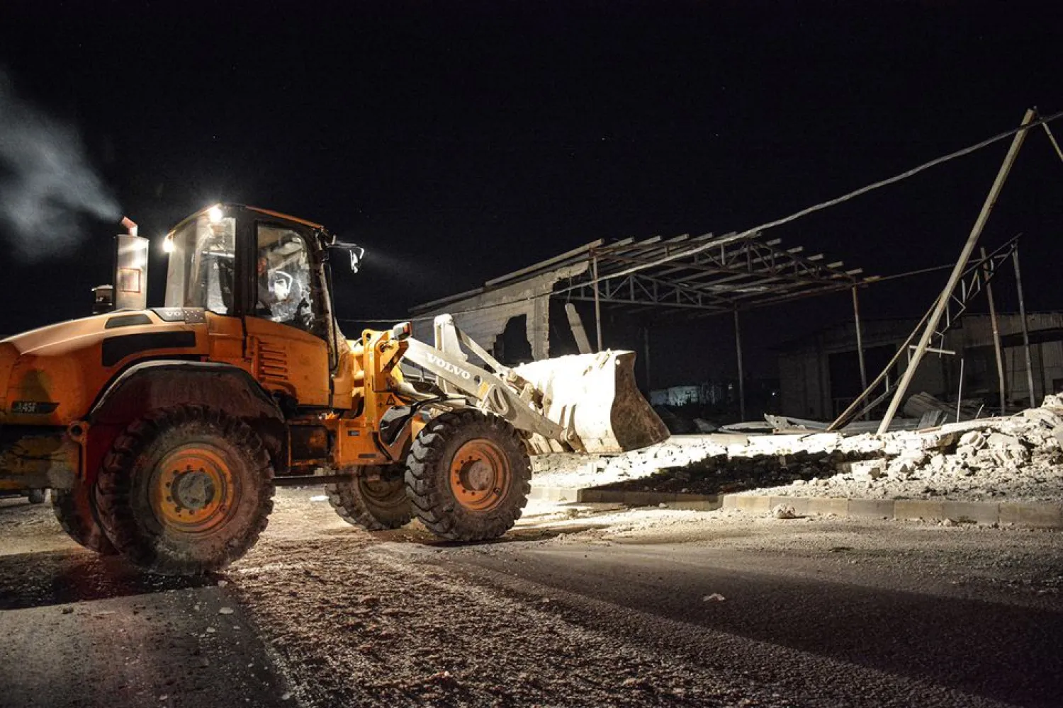 A man operates a front loader at a site after pre-dawn raids on the Mediterranean port region of Latakia, Syria, in this handout picture released on May 5, 2021. (SANA/Handout via Reuters)