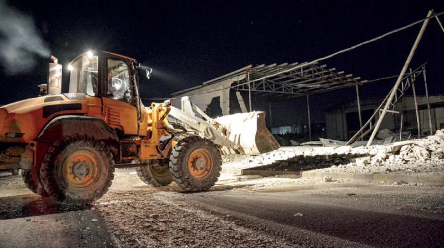 آلية تزيل ركام الدمار بعد قصف إسرائيلي في ريف اللاذقية أول من أمس (رويترز)