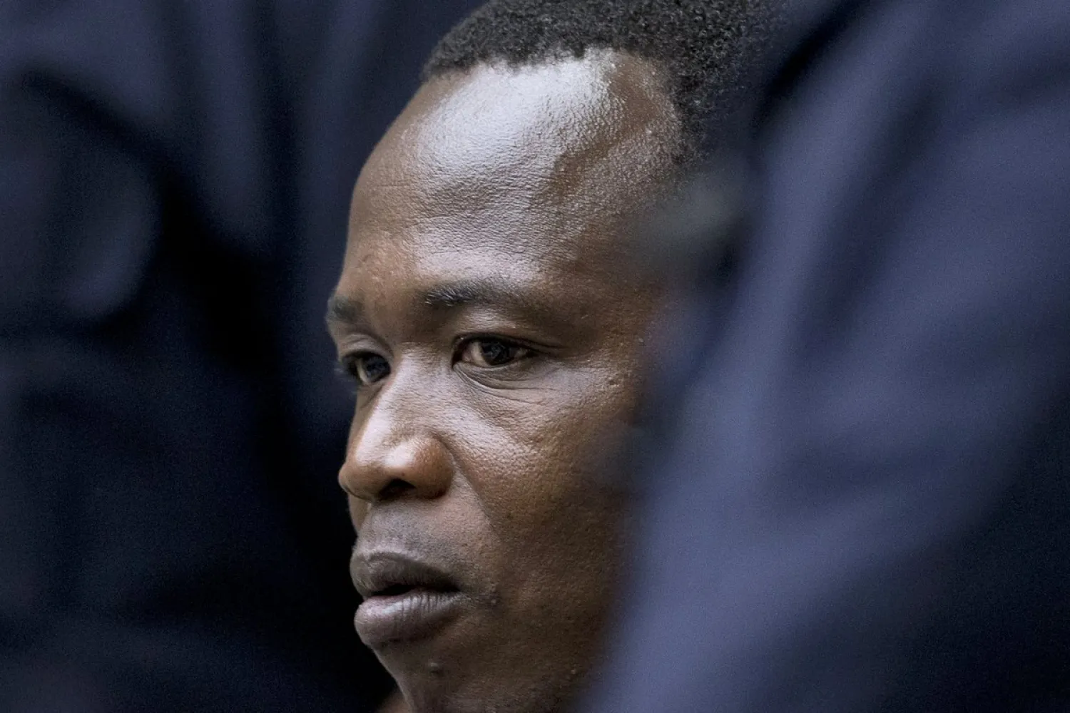 In this Tuesday, Dec. 6, 2016 file photo, Dominic Ongwen, a senior commander in the Lord's Resistance Army, whose fugitive leader Kony is one of the world's most-wanted war crimes suspects, is flanked by two security guards as he sits in the courtroom of the International Court in The Hague, Netherlands. (AP Photo/Peter Dejong, Pool, File)