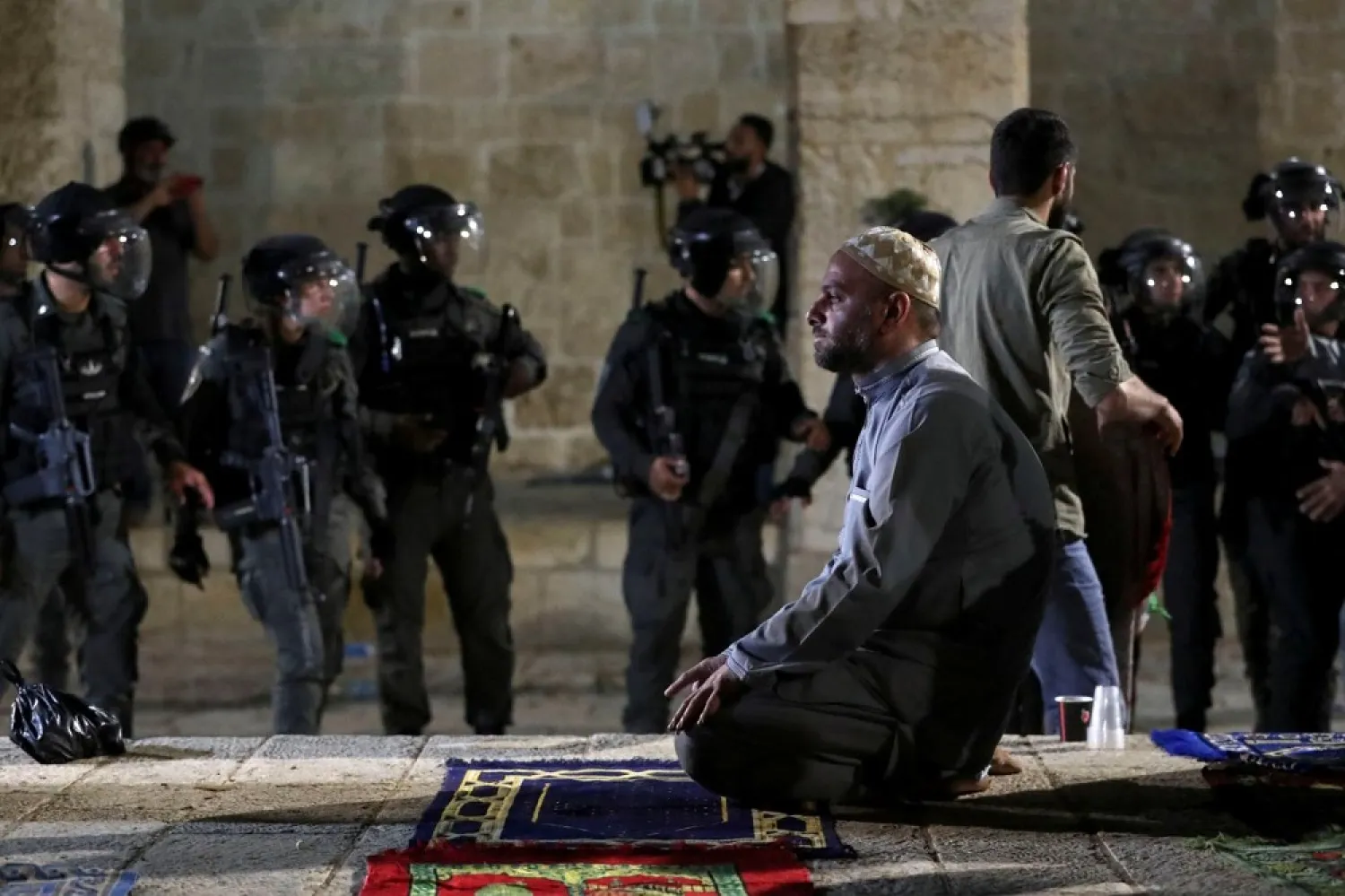 A Palestinian man prays as Israeli police gather during clashes at the Al-Aqsa Mosque, amid tension in the Sheikh Jarrah neighborhood, in Jerusalem's Old City, on Friday. (Reuters)