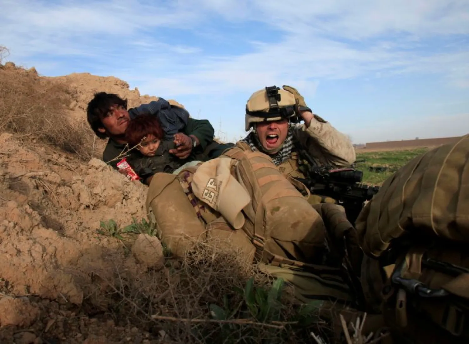 US Marine Lance Corporal Chris Sanderson, from Flemington, New Jersey shouts as he tries to protect an Afghan man and his child after Taliban fighters opened fire in the town of Marjah, in Nad Ali district, Helmand province, Afghanistan, Feb | AFP