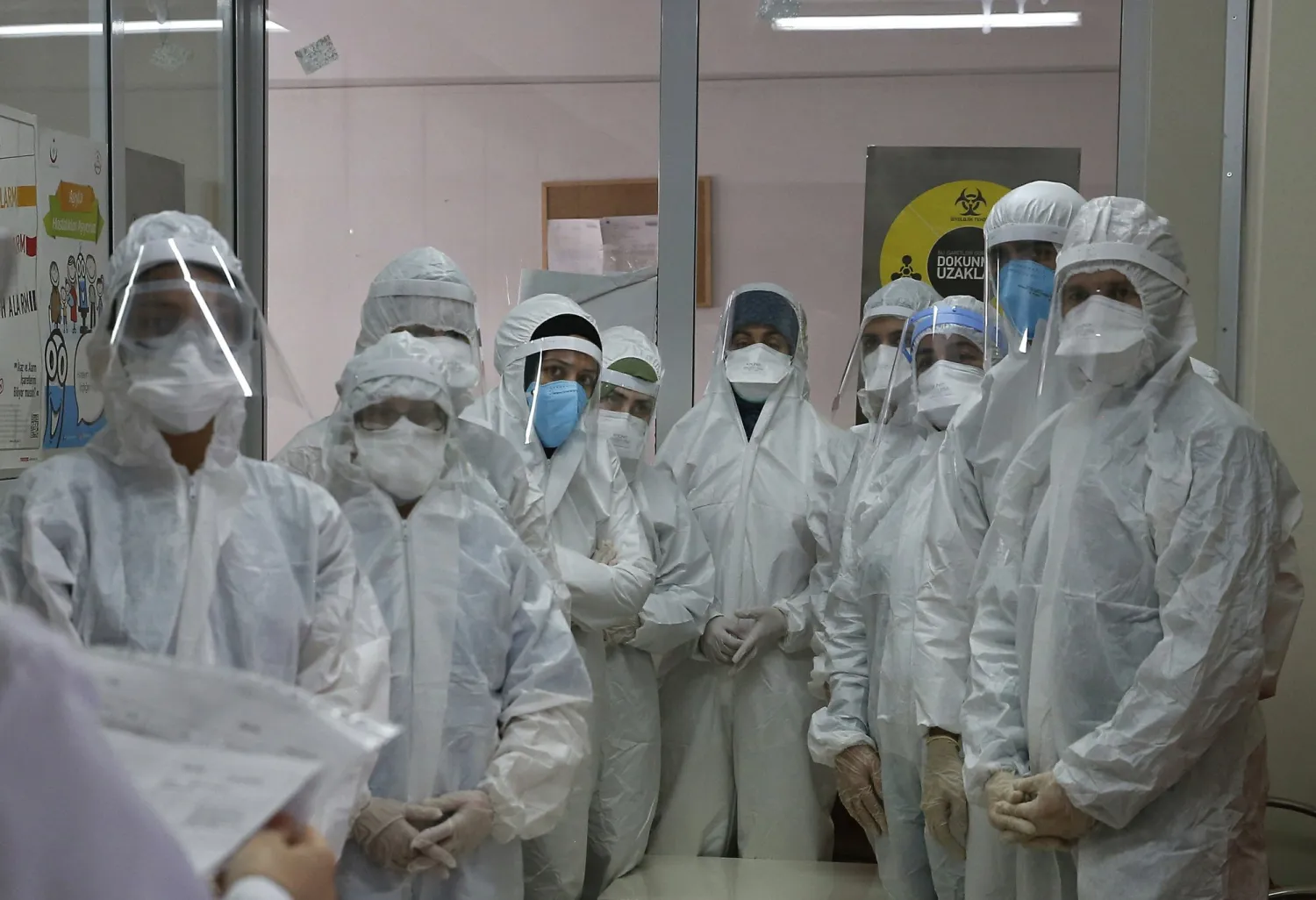 FILE - In this Friday, May 15, 2020, file photo, a team of Turkey's Health Ministry's coronavirus contact tracing team, clad in white protective gear, masks and face shields are briefed in Istanbul. 