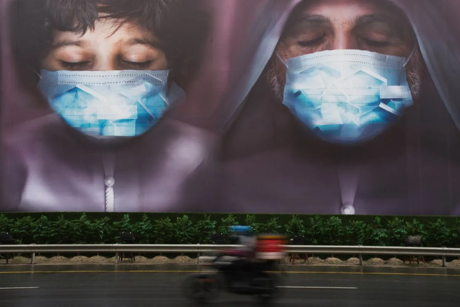 In this April 15, 2020 file photo, a motorcycle delivery man rides past a billboard urging people to stay home over the coronavirus pandemic in Dubai, United Arab Emirates. (AP)