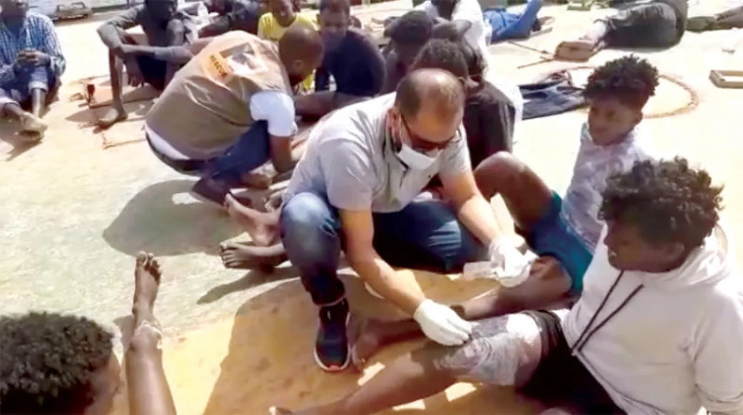 عمال يقدمون الإسعافات الأولية لمهاجرين تم إنزالهم في قاعدة طرابلس البحرية (البحرية الليبية)