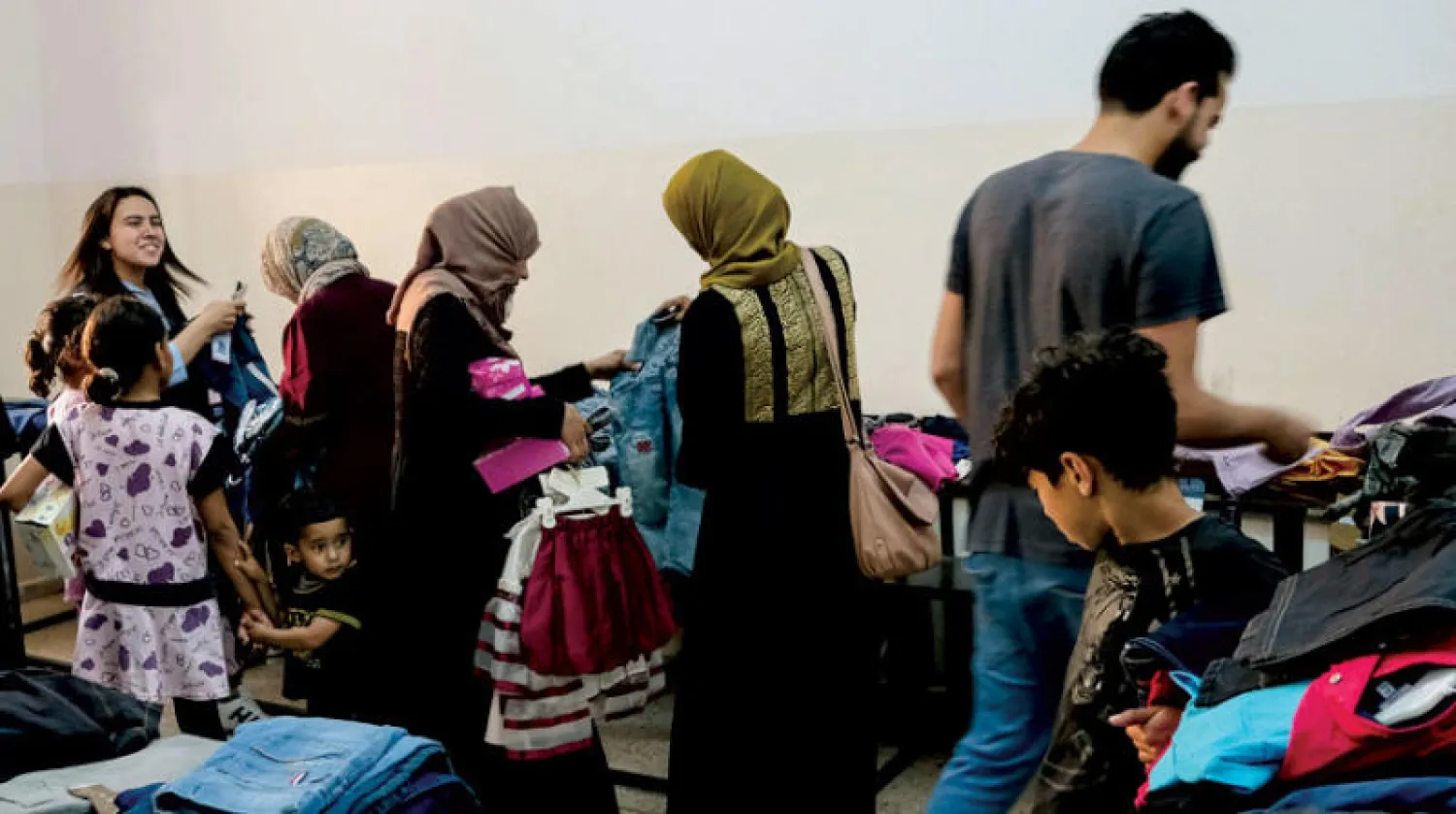 ليبيون يشترون ملابس عيد الفطر لأبنائهم في سوق بمدينة بنغازي (رويترز)