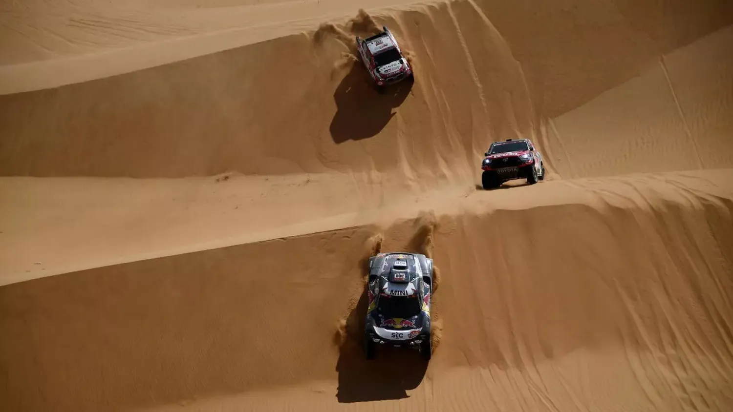 Competitors up to their hub caps in sand during this year's Dakar. (AFP)