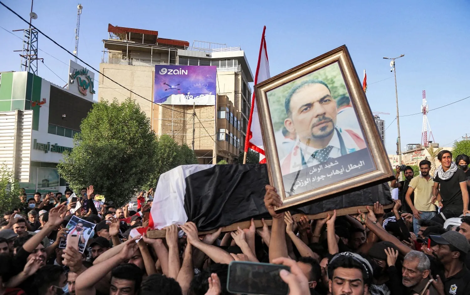 People chant slogans as they march with the body of renowned Iraqi anti-government activist Ihab al-Wazni during a funerary procession in the central city of Karbala on May 9, 2021. (AFP)
