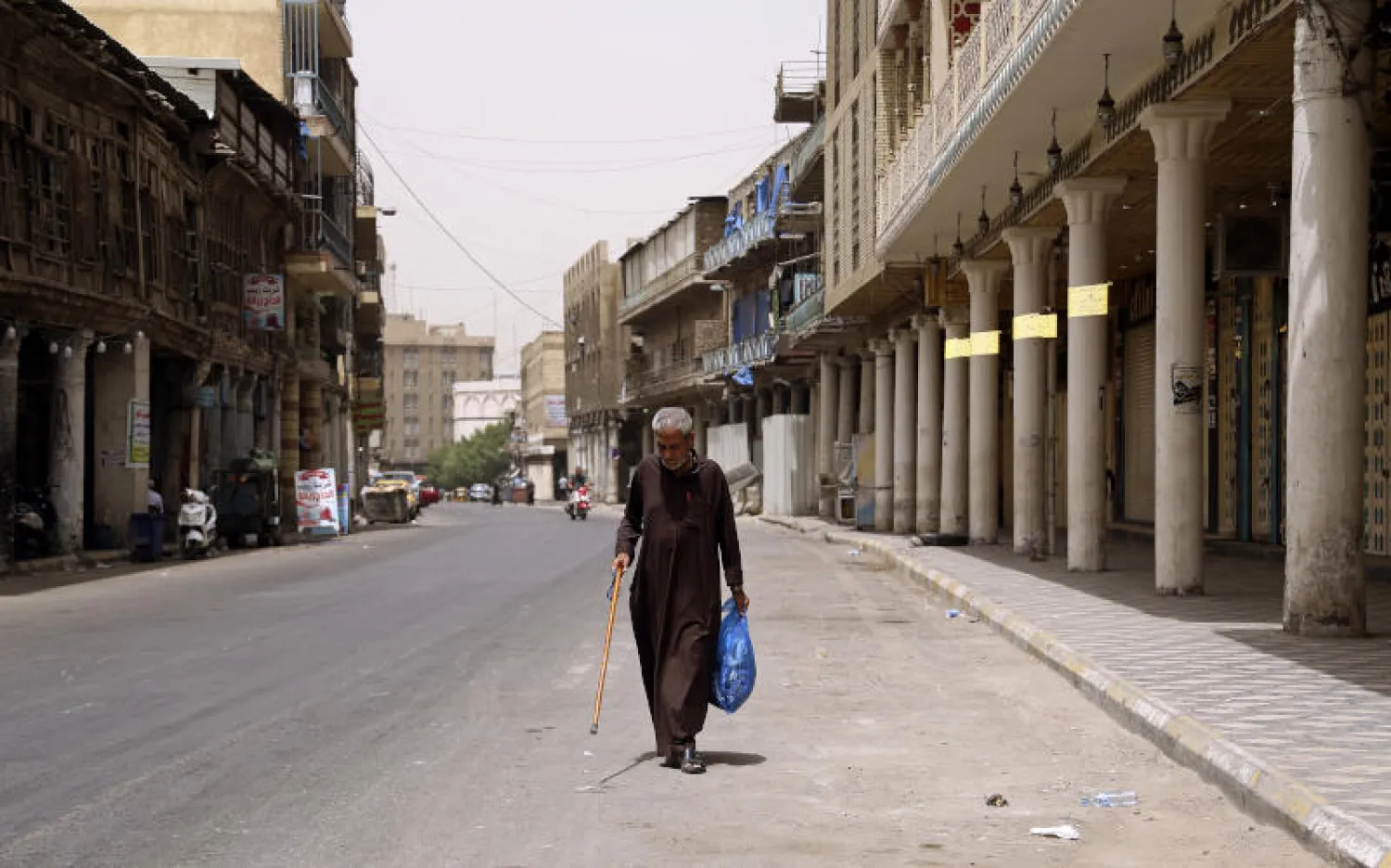 رجل يسير في شارع تجاري فارغ بسبب انتشار فيروس كورونا في وسط بغداد (أ.ب)