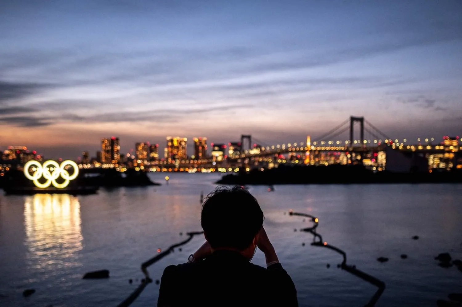 A man takes pictures of the Olympic rings at the Odaiba waterfront in Tokyo. (AFP)
