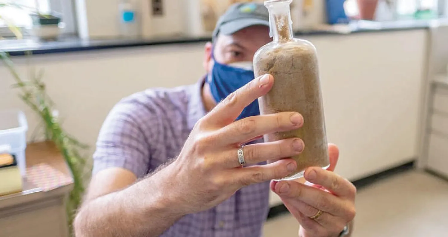 أحد العلماء يعرض الزجاجة التي خزنت فيها البذور (نيويورك تايمز - جامعة ميشيغان)