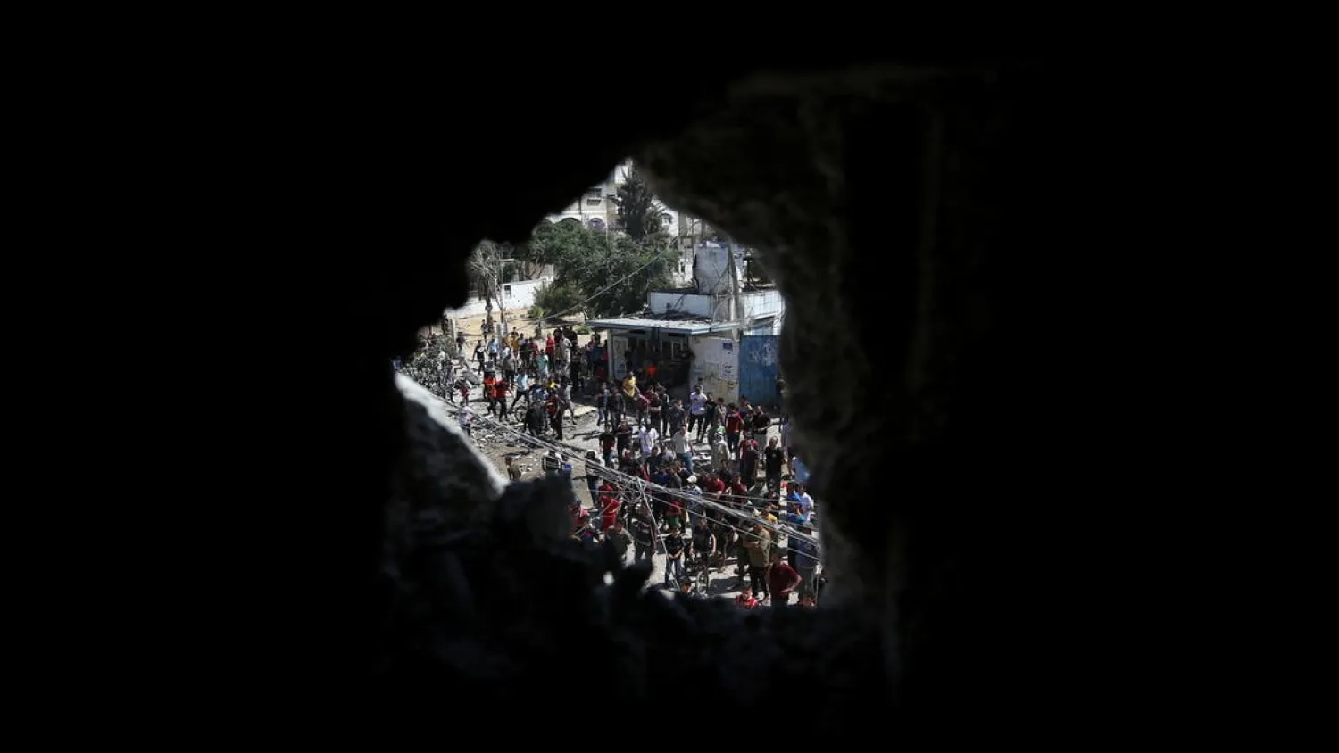 Palestinians are seen through a damaged house as they gather following an Israeli air strike, amid a flare-up of Israeli-Palestinian violence, in the southern Gaza Strip May 12, 2021. (Reuters)
