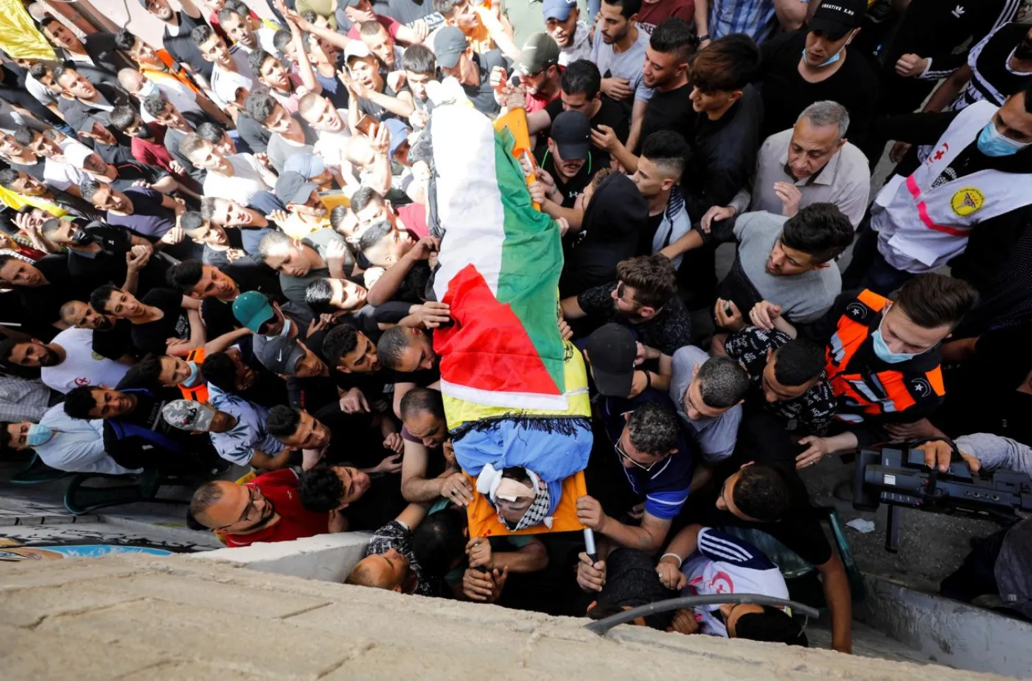 Mourners carry the body of 26-year-old Palestinian Hussein al-Titi, who was killed by Israeli forces in al-Fawwar refugee camp in the Israeli-occupied West Bank on 12 May 2021 (Reuters)

