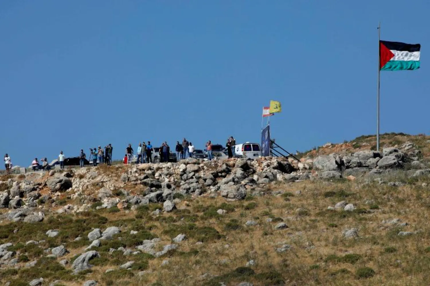لبنانيون يتجمعون قرب الشريط الحدودي قبالة مستعمرة المطلة الإسرائيلية (أ.ف.ب)