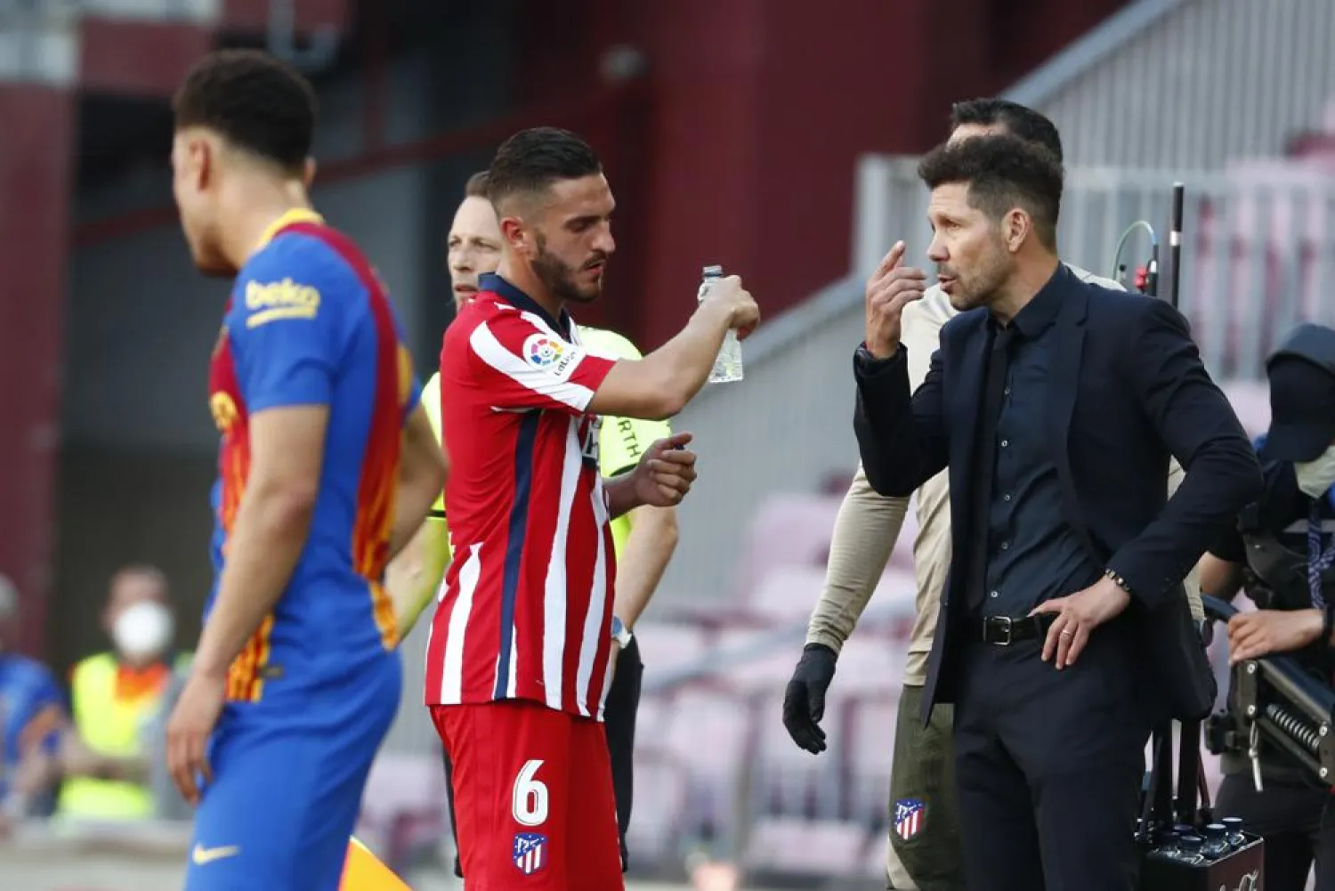 Atletico Madrid's coach Diego Simeone, right, speaks with his player Koke during a water break during the La Liga match against FC Barcelona at the Camp Nou stadium in Barcelona, Spain, May 8, 2021. (AP)