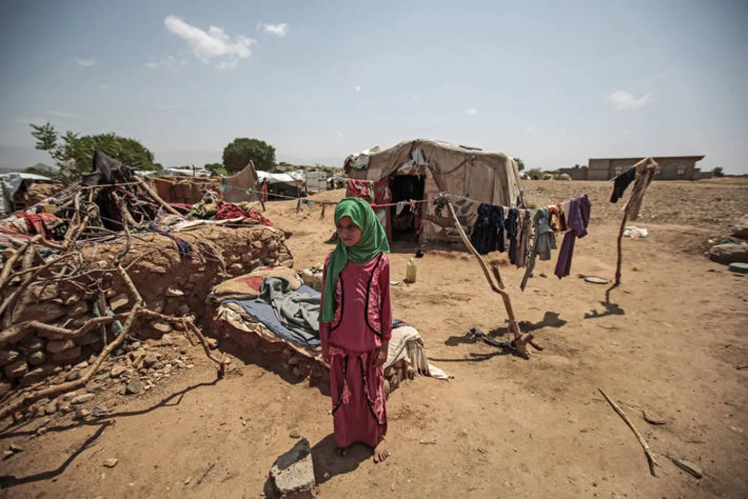  An internally displaced young Yemeni girl stands outside her hut (AFP)
