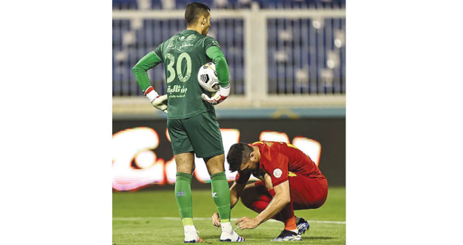لاعب من ضمك يربط حذاء حارس الفريق  خلال مواجهة الاتحاد الأخيرة (تصوير: عدنان مهدلي)