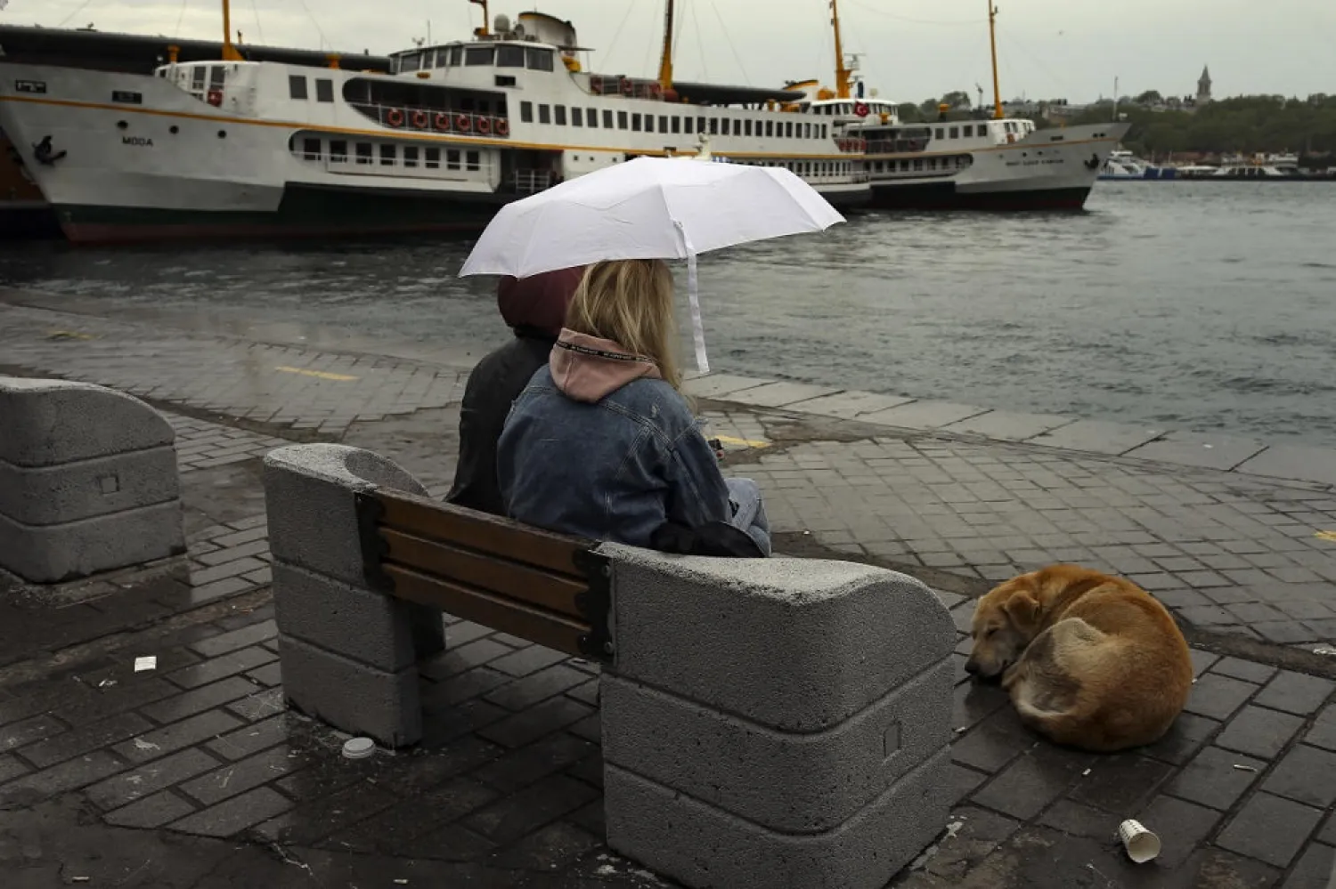 People sit under rain by the nearly-deserted Golden Horn market amid strict lockdown in Turkey. (AP file photo)