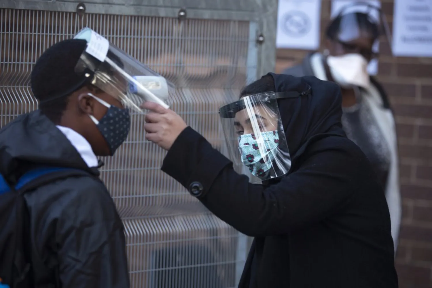 The temperature of a grade 7 pupil is taken as he returns to the Meldene Primary School in Johannesburg Monday, June 8, 2020. Schools were closed down almost three months ago in a bid to contain the spread of the coronavirus and have started with the return to classes of grade 7 and 12 classes under strict conditions. (AP Photo/Denis Farrell)
