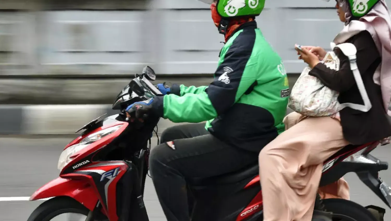A Gojek rider transports a passenger in Jakarta - AFP