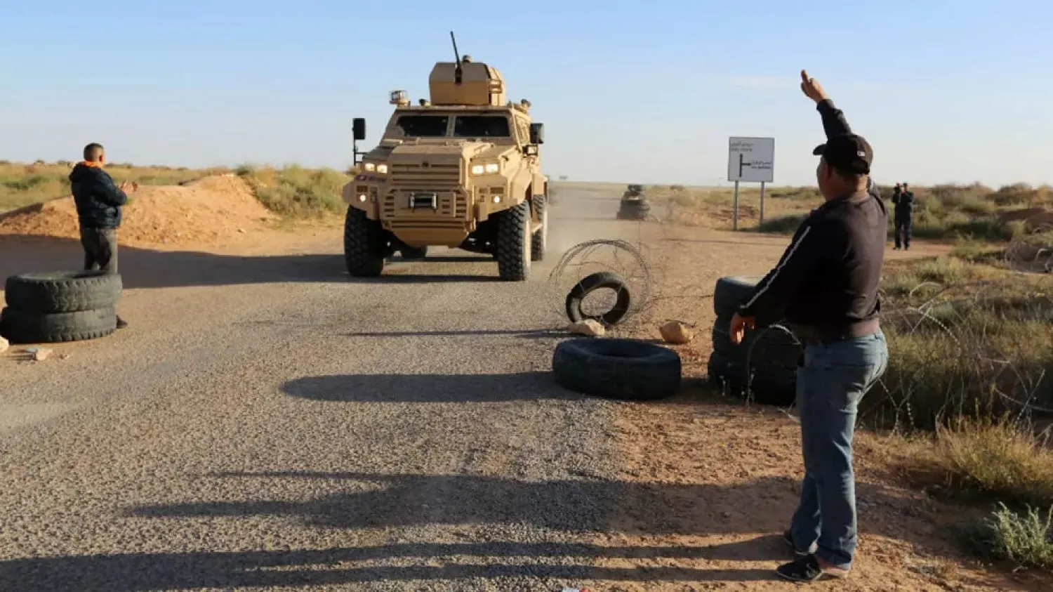 Tunisian men salute National Guard forces on March 19, 2018. (AFP)