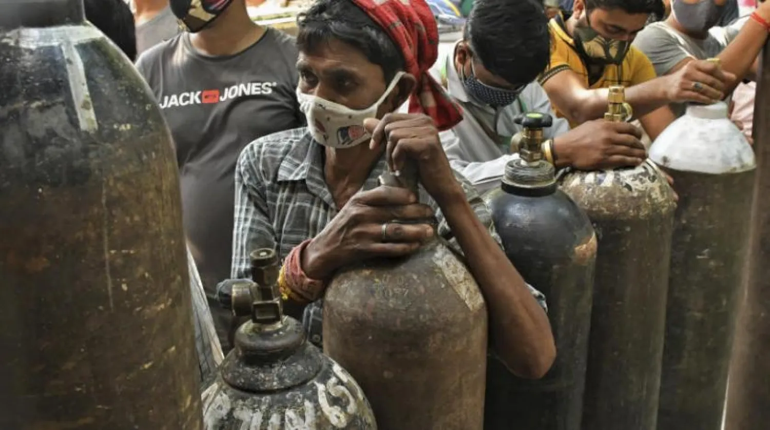 Yeni Delhi’deki bir gaz tedarik tesisinde koronavirüs hastaları için oksijen tüplerini doldurmayı bekleyen insanlar (AP)