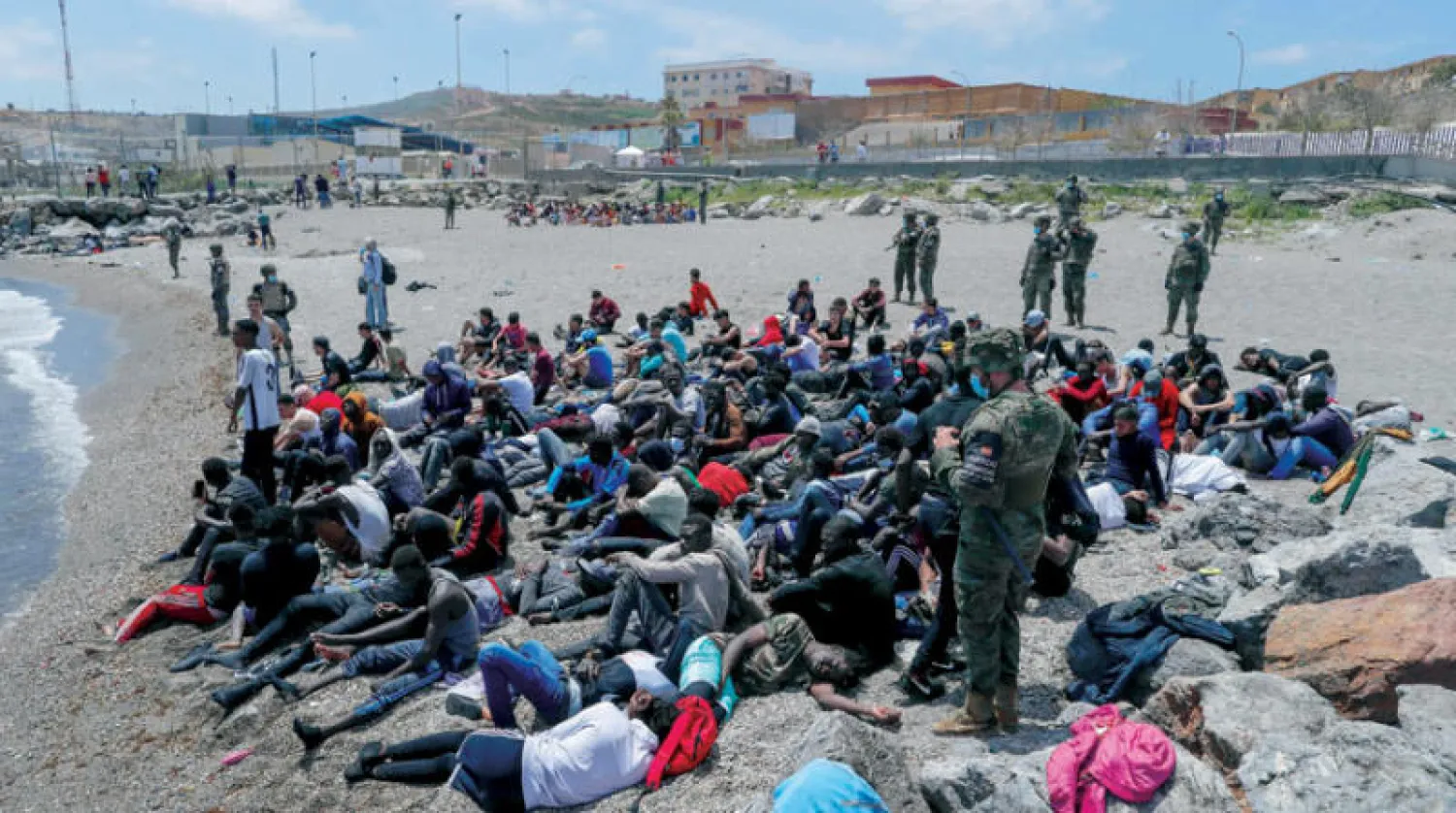 قوات الأمن الإسباني تحرس عدداً من المهاجرين الذين دخلوا سبتة بطريقة غير شرعية أمس (رويترز)