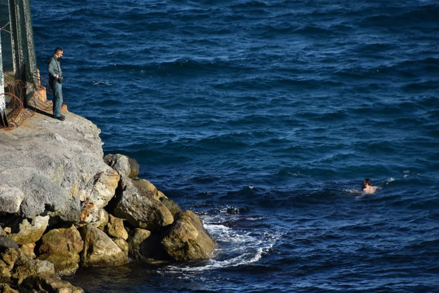 A migrant crosses the Spanish-Moroccan border in the presence of a Spanish civil guard in Ceuta, Spain, May 17, 2021. (Reuters)