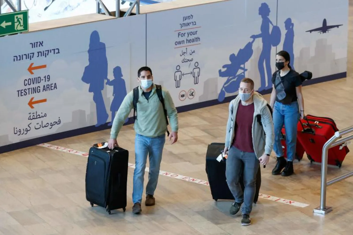 أشخاص يضعون الكمامات في مطار بن غوريون الإسرائيلي بالقرب من تل أبيب (أ.ف.ب)