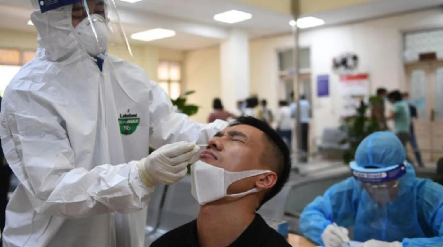 Hanoi’de bir hemşire bir kişiye kovid-19 testi yaptığı sırada. (AFP)