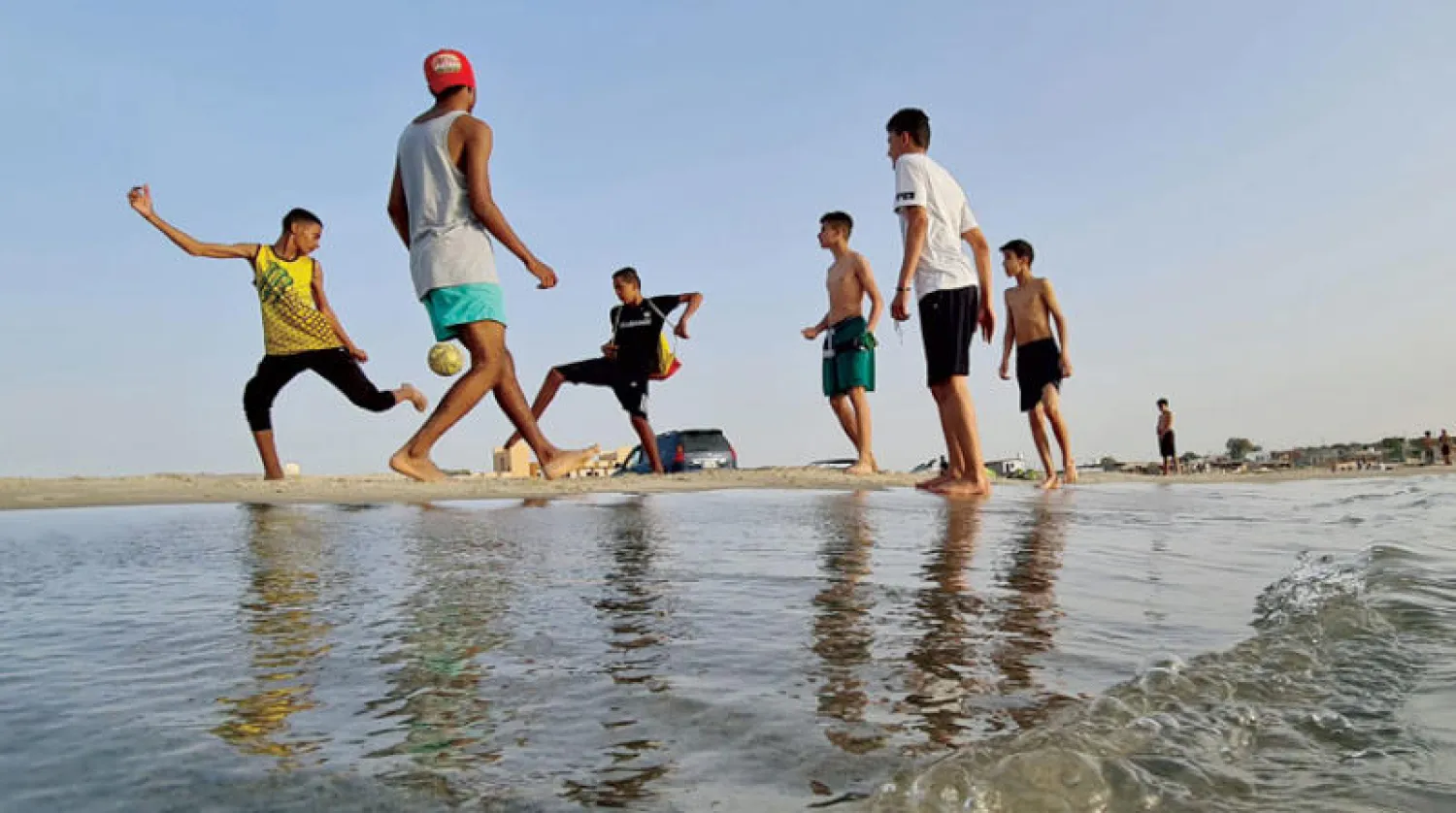 شبان ليبيون يلعبون كرة القدم على الشاطئ في بلدة القرة بوللي شرق العاصمة (أ.ف.ب)
