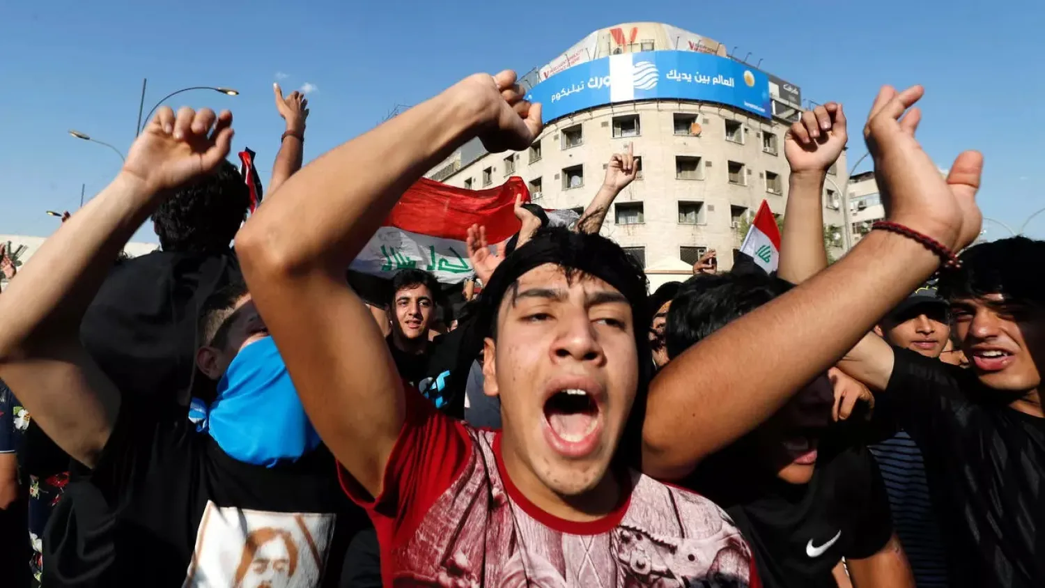 Iraqis pump their fists as they demonstrate in Tahrir Square in Baghdad on May 25, 2021, to demand accountability for a recent wave of killings targeting activists. (AFP)