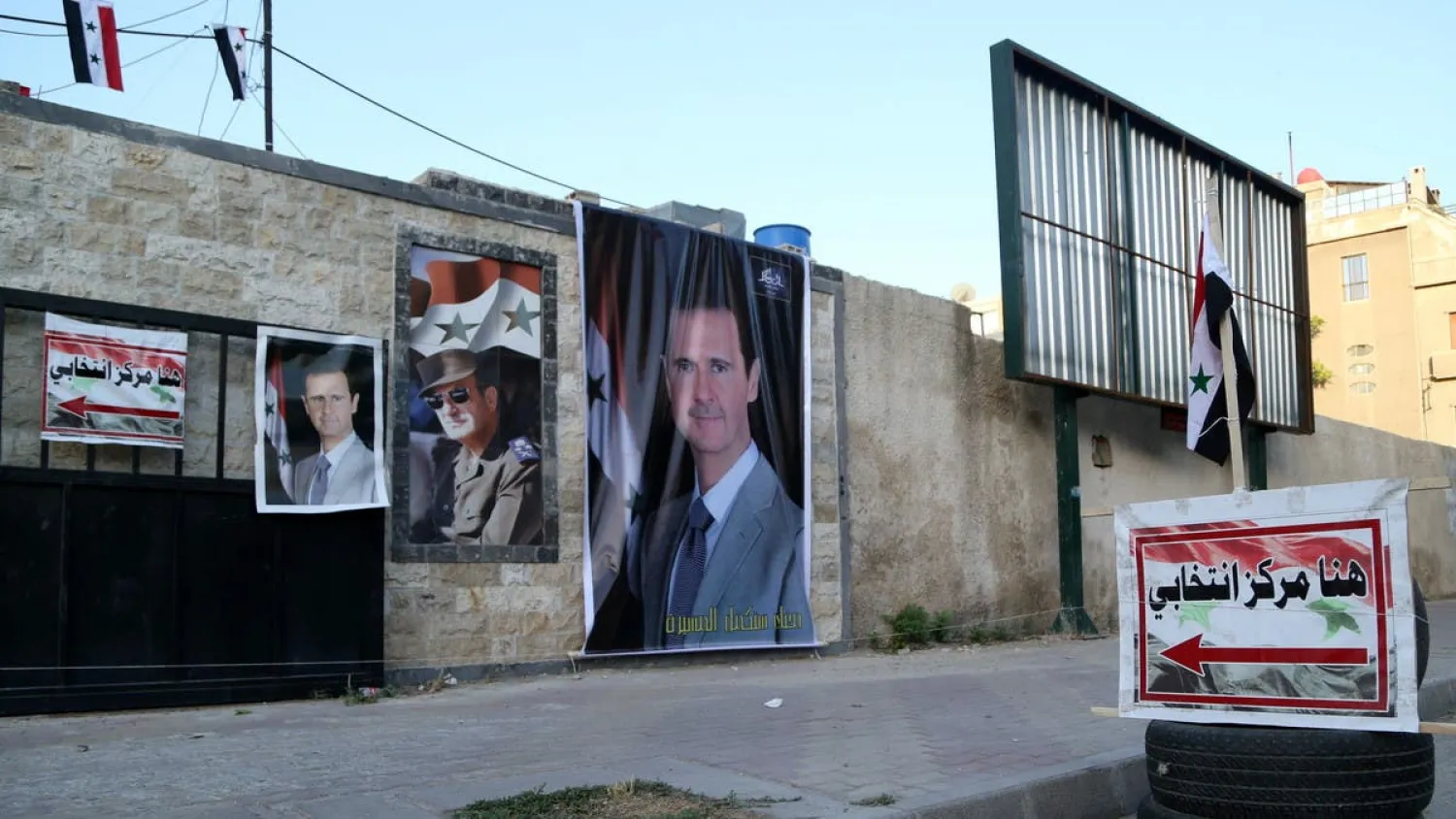 Posters of Syria’s president Bashar Assad are seen outside a polling station before polls open for the presidential elections, in Damascus, Syria May 26, 2021. (Reuters)
