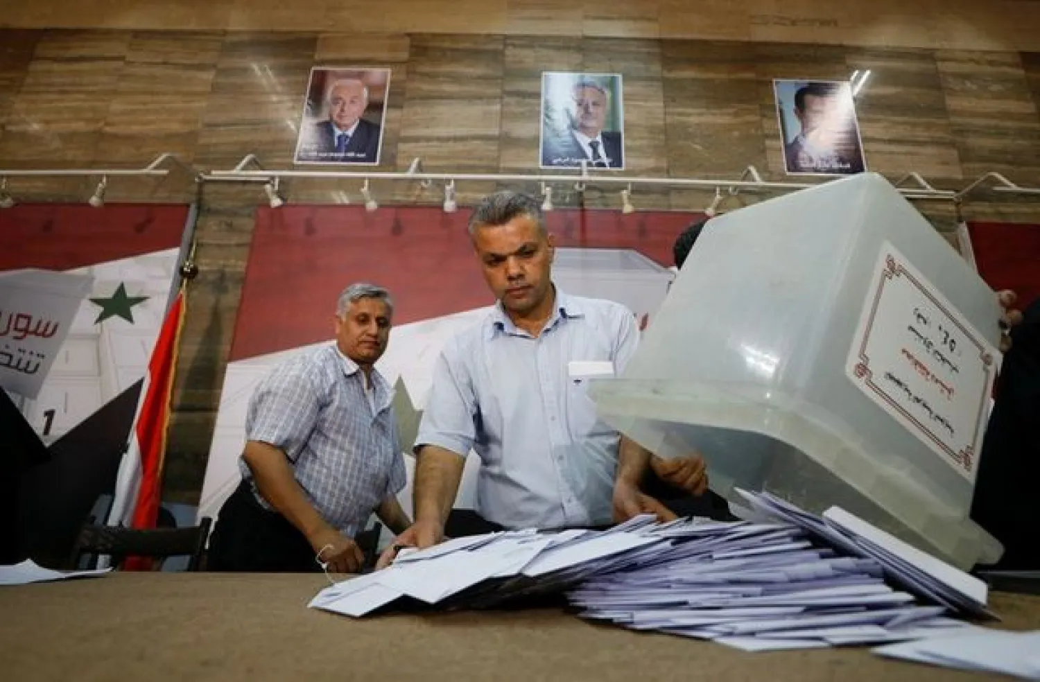 A poll worker empties a ballot box to count votes after polling stations closed during the country's presidential elections in Damascus (Reuters)
