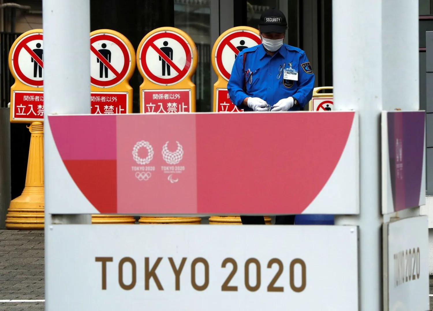 A security personnel and off-limits displays are seen near a banner for the Tokyo 2020 Olympics and Paralympics. Reuters
