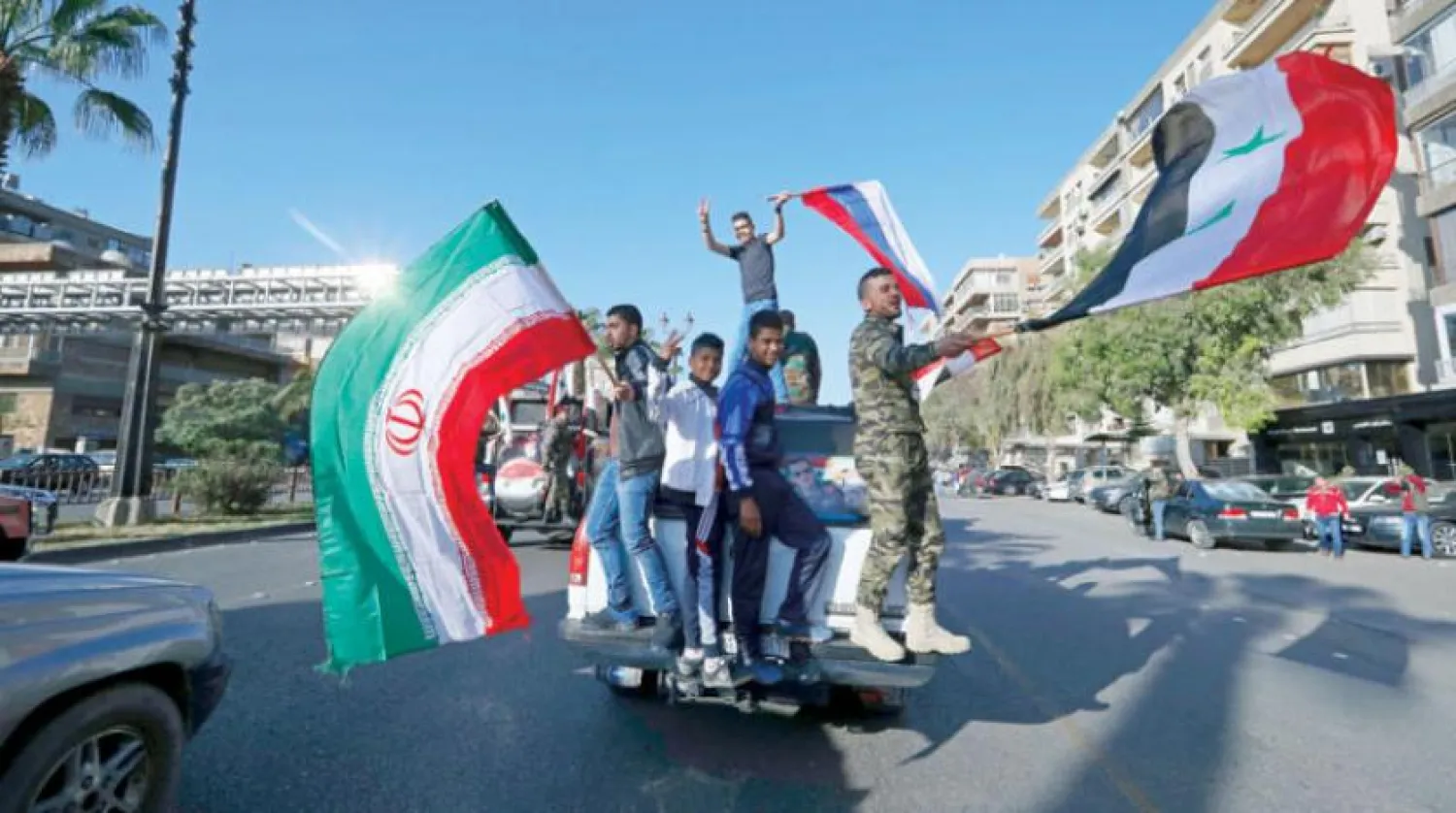Syrians on a street in Damascus carrying the flags of their country, Russia and Iran, April 2019 (AP).