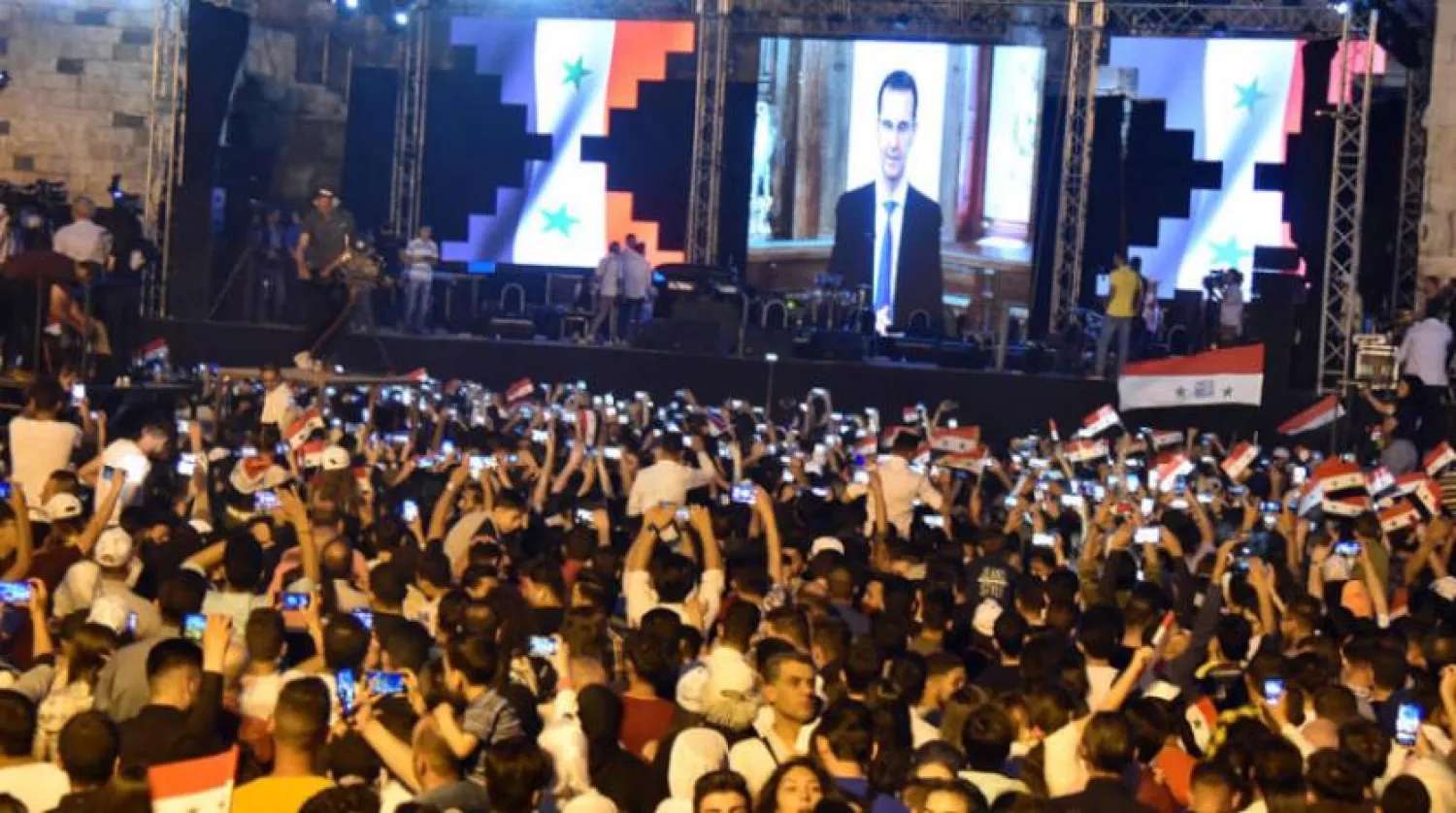 Esed destekçileri, yeniden Devlet Başkanı seçilen Beşşar Esed’in Cuma akşamı Şam meydanından yayınlanan konuşmasını dinlerken (EPA)
