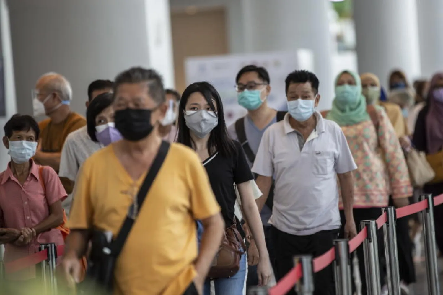 أشخاص ينتظرون عملية التسجيل لتلقي لقاح «كورونا» بمركز للتطعيم في كوالالمبور (أ.ف.ب)